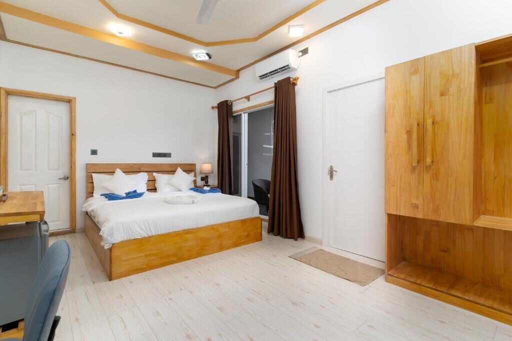 Bright air-conditioned room with a king bed and wooden wardrobe at Tropico Villa